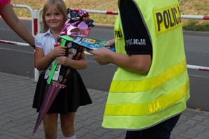 zdjęcie przedstawia policjantów rozdających odblaski i broszury profilaktyczne