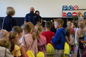 zdjęcie przedstawia policjanta rozmawiającego z dziećmi