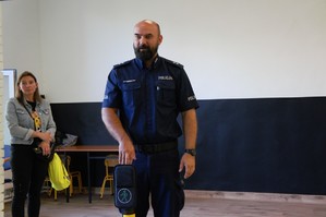 zdjęcie przedstawia policjanta pokazującego sygnalizację świetlną dla pieszych