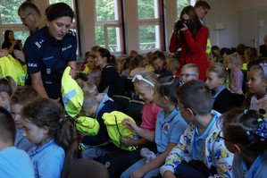 zdjęcie przedstawia zastępcę komendanta rozdającą odblaskowe plecaki