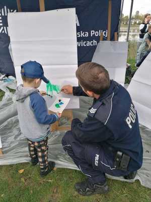 zdjęcie przedstawia: policjanta z dzieckiem malującego farbami