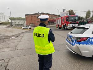 zdjęcie przedstawia policjanta stojącego przy radiowozie