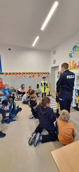 zdjęcie przedstawia policjanta z uczniami szkoły podstawowej