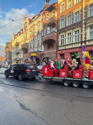 zdjęcie przedstawia samochód ciągnący na lawecie sanie z uczestnikami parady