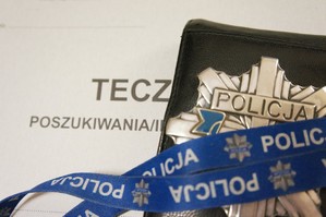 zdjęcie przedstawia odznakę policyjną leżącą na teczce z napisem poszukiwania