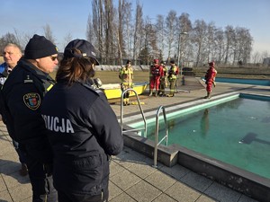 zdjęcie przedstawia służby mundurowe nad zamarzniętym basenem