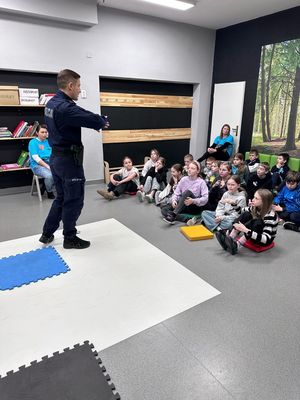 zdjęcie przedstawia policjanta rozmawiającego z uczniami