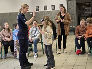 zdjęcie przedstawia policjantkę i dziewczynkę z założonymi goglami