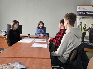 osoby siedzące przy stole rozmawiające z pracownikami policji