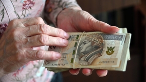 zdjęcie przedstawia starszą osobę trzymającą pieniądze