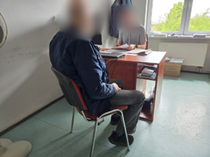 zdjęcie przedstawia policjanta stawiającego zarzuty zatrzymanemu włamywaczowi