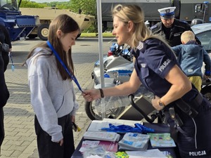 zdjęcie przedstawia policjantkę dająca smycz dziewczynce