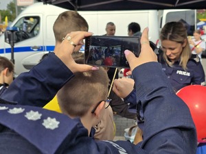 zdjęcie przedstawia zbliżenie na aparat robiący zdjęcie dzieciom na stoisku profilaktycznym