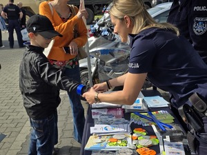 zdjęcie przedstawia policjantkę dającą odblask chłopcku