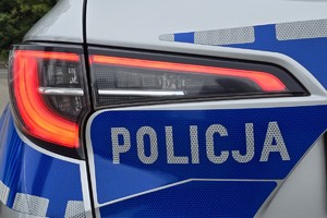 zdjęcie przedstawia zbliżenie na lampę z radiowozu i napis policja