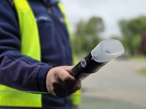 zdjęcie przedstawia policjanta trzymającego urządzenie do badania trzeźwości