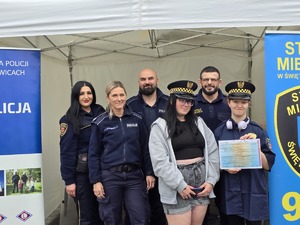 zdjęcie przedstawia policjantów oraz strażników miejskich robiących sobie zdjęcie z uczestnikami festynu