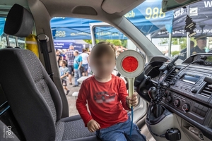 dziecko w radiowozie trzymające tarczę Stop
