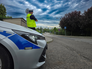 zdjęcie przedstawia radiowóz i policjanta mierzącego prędkość
