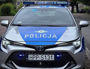 zdjęcie przedstawia radiowóz z włączonymi sygnałami