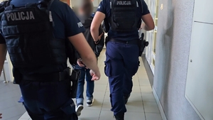 zdjęcie przedstawia policjantów prowadzących osobę zatrzymaną