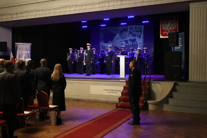 zdjęcie przedstawia dowódcę uroczystości a w tle orkiestra na scenie