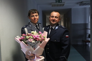 zdjęcie przedstawia policjanta i policjantkę z kwiatami