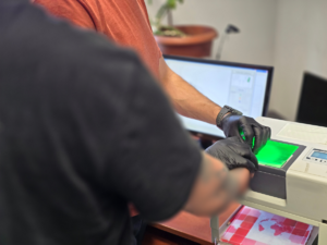 zdjęcie przedstawia technika pobierającego odciski palców mężczyźnie