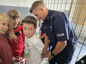 zdjęcie przedstawia policjanta i dzieci na prelekcji w komendzie