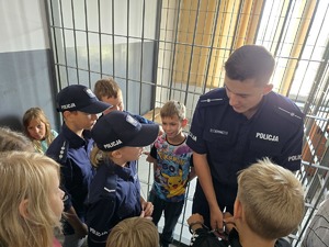 zdjęcie przedstawia policjanta i dzieci na prelekcji w komendzie