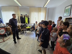 zdjęcie przedstawia policjanta i dzieci na prelekcji w komendzie
