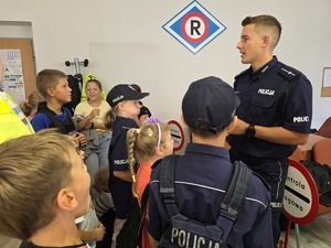 zdjęcie przedstawia policjanta i dzieci na prelekcji w komendzie