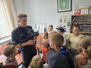 zdjęcie przedstawia policjanta i dzieci na prelekcji w komendzie