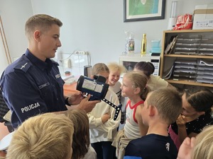 zdjęcie przedstawia policjanta i dzieci na prelekcji w komendzie