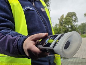 zdjęcie przedstawia policjanta z alkomatem