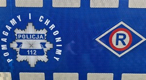 zdjęcie przedstawia naklejkę z napisem pomagamy i chronimy oraz znaczek ruchu drogowego