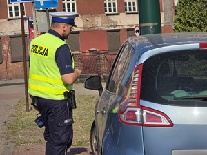 zdjęcie przedstawia policjanta kontrolującego pojazd