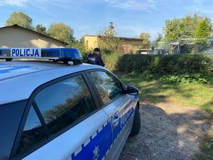 zdjęcie przedstawia radiowóz a w tle dzielnicowego