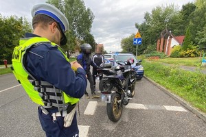 Zdjęcie przedstawia policjanta kontrolującego motocyklistę