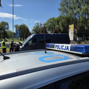 zdjęcie przedstawia policjantów podczas kontroli drogowej i napis na radiowozie policja