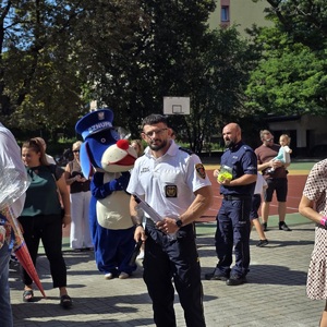 zdjęcie przedstawia: policjantów i maskotkę policji na rozpoczęciu roku szkolnego