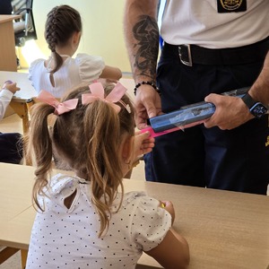 zdjęcie przedstawia: strażnika miejskiego rozdającego odblaski