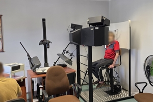 zdjęcie przedstawia technika kryminalistyki robiącego zdjęcia mężczyźnie