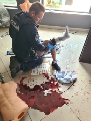 zdjęcie przedstawia policjanta udzielającego pierwszej pomocy
