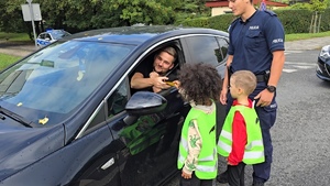 zdjęcie przedstawia: policjanta i dzieci z przedszkola wręczające kierowcy medal