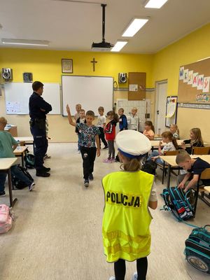 zdjęcie przedstawia: policjanta rozmawiającego z dziećmi w szkole