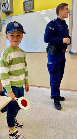 zdjęcie przedstawia: policjanta rozmawiającego z dziećmi w szkole