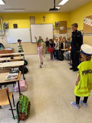 zdjęcie przedstawia: policjanta rozmawiającego z dziećmi w szkole
