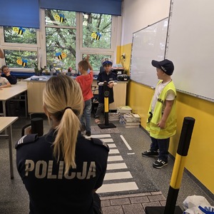 zdjęcie przedstawia: policjantkę i uczniów przebranych za policjantów