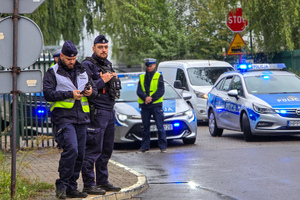 zdjęcie przedstawia: policjantów i radiowozy